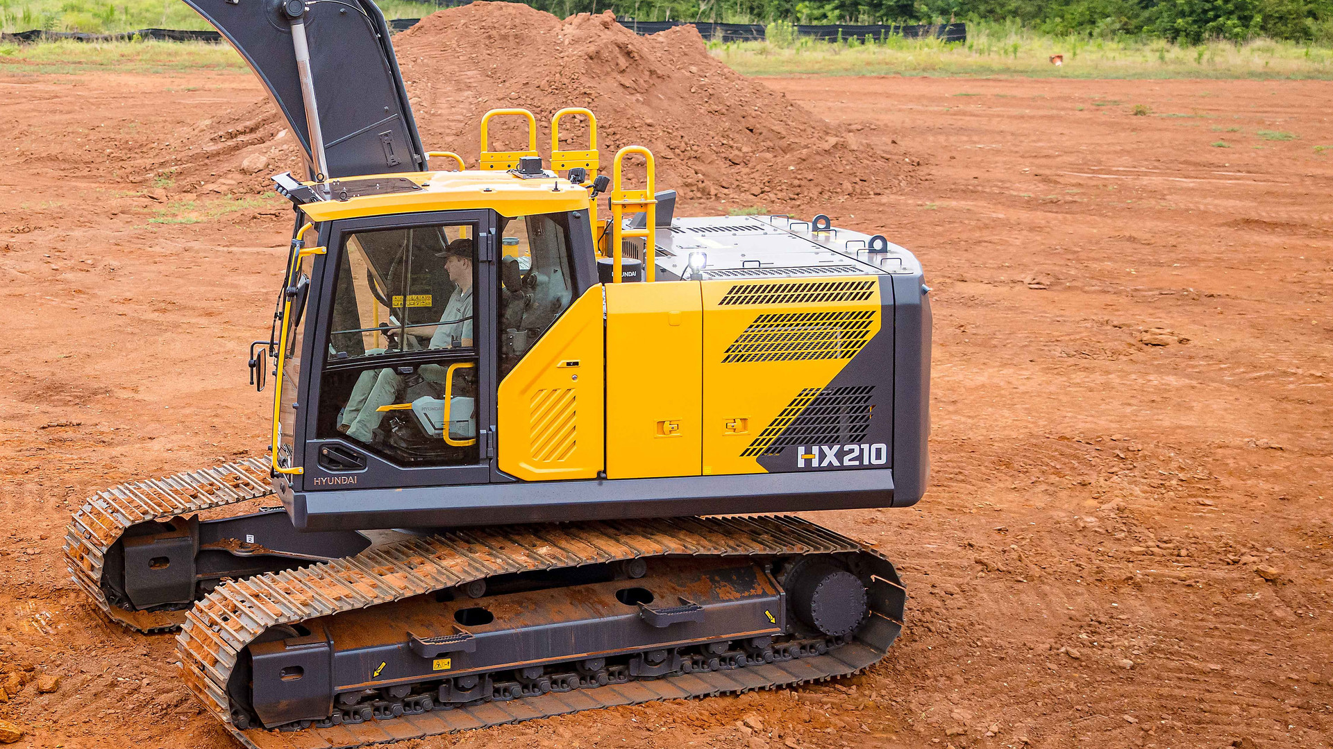 Hyundai HX210L excavator side view with the HX210 model badge on the engine cover and long undercarriage