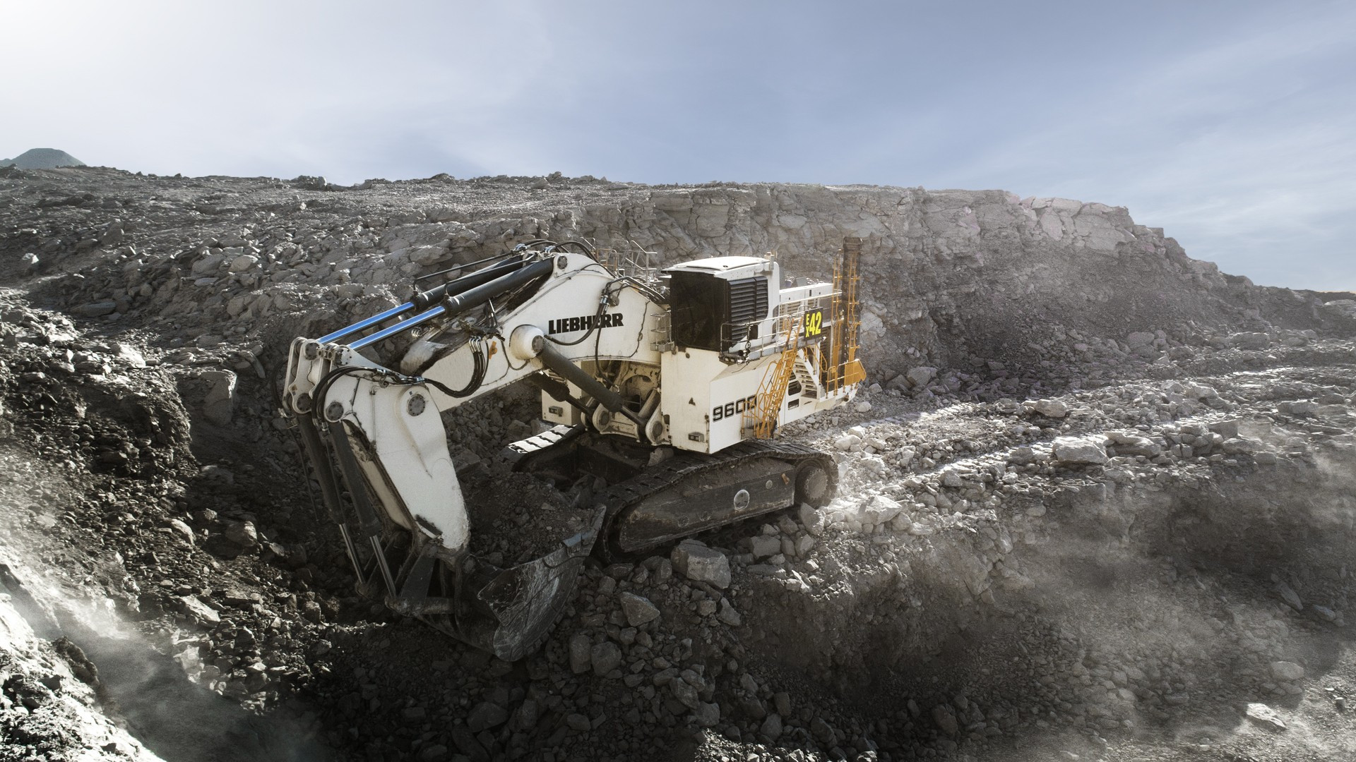 Liebherr R 9600 mining excavator digging a rock face in an open pit, 9600 badge visible on the machine house