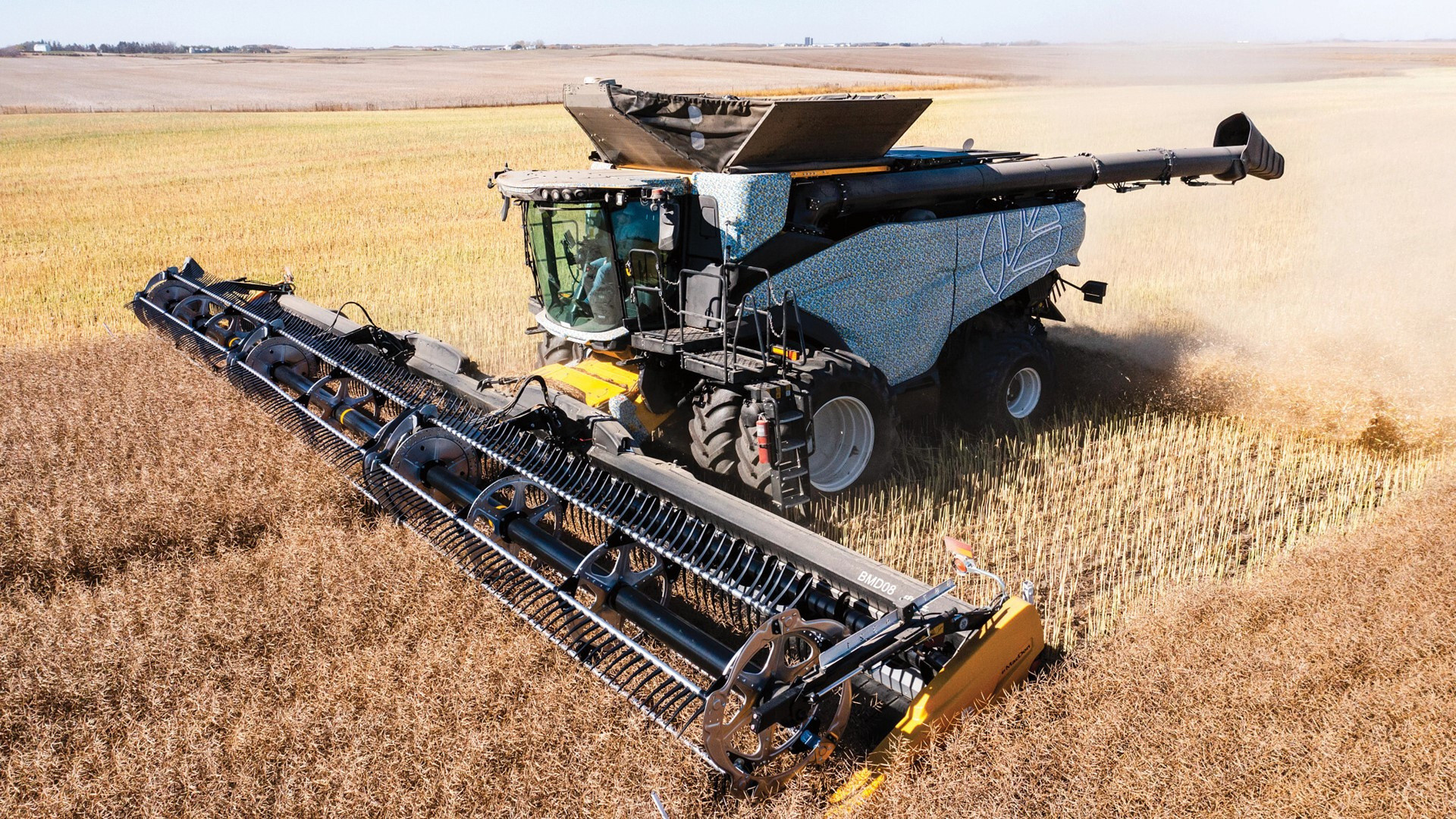 New Holland CR11 combine harvesting a canola crop with a wide draper header