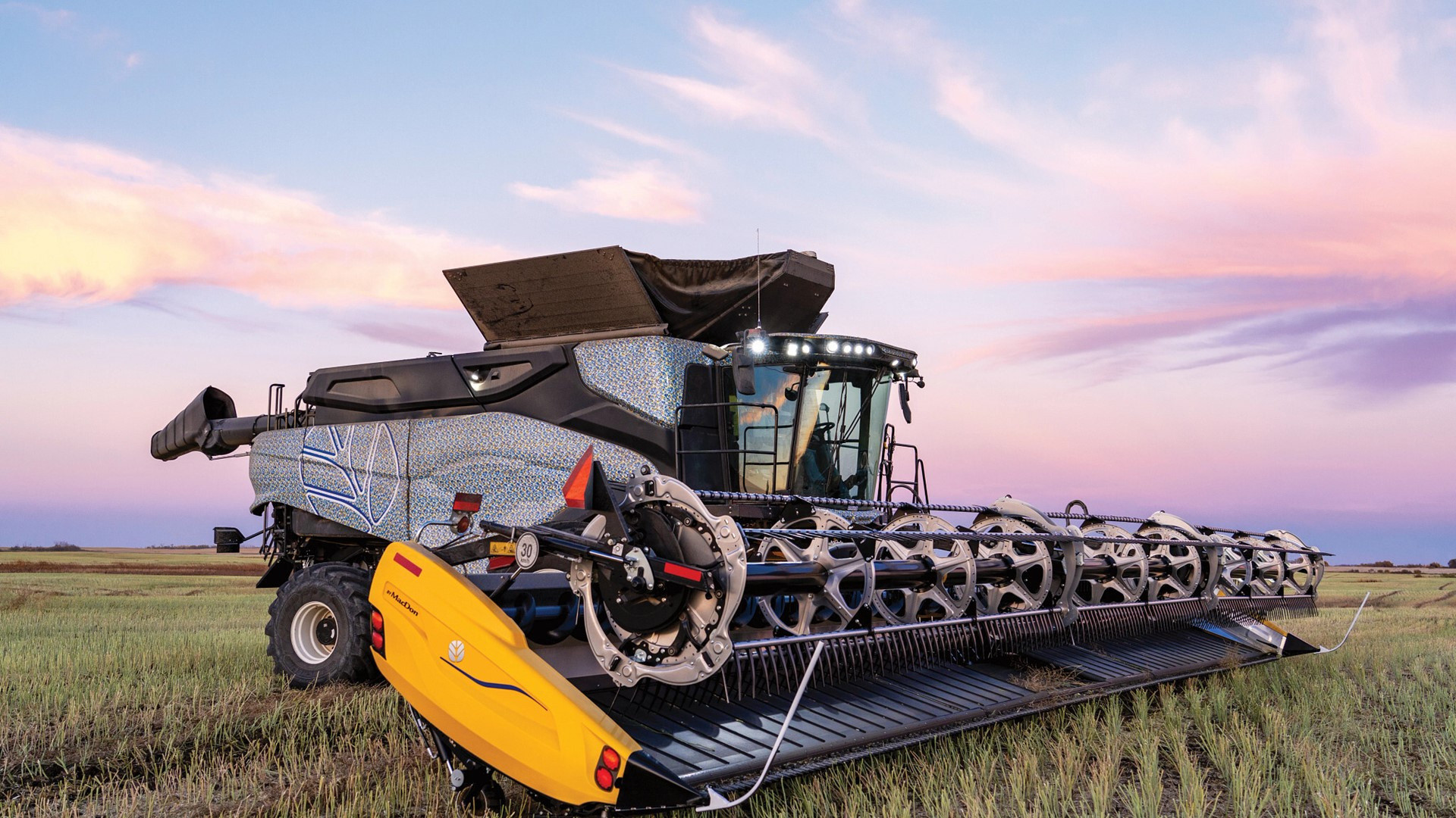 New Holland CR11 combine with draper header standing in a stubble field at sunset